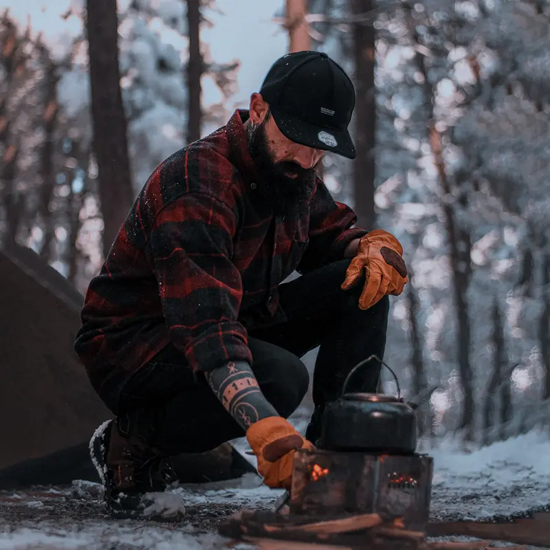 Man making tea while camping in snowy weather