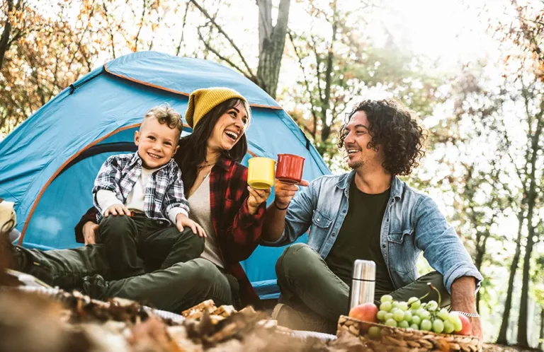 Young family camping with toddler at tent with picnic